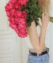 Young stylish woman holding a big bouquet of pink roses. 