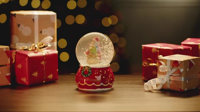 Christmas snowglobe and Christmas gifts on table