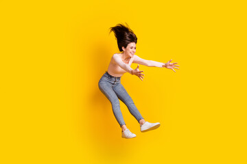 Full size photo of young lovely crazy smiling excited girl jumping catch surprise present isolated on yellow color background