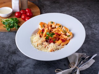 Penne Pasta with Shrimps, lemon and parmesan chhese on white plate on dark background, top view....