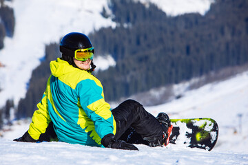 man sitting with snowboard on the top of the hill with beautiful view