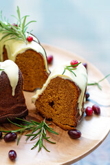 Christmas caramel cake, cutaway, decorated with white chocolate, cranberries and rosemary on a wooden stand. Festive baked goods. Soft selective focus. Vertical, close-up.