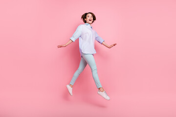 Fototapeta na wymiar Full length body size photo woman smiling jumping up cheerful isolated pastel pink color background
