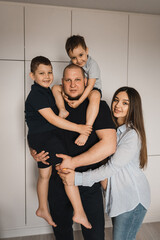 Portrait of loving family with two sons. Happy caucasian family of four people. Pregnant woman hugs her husband and sons. Sons are in father's arms. Selective focus