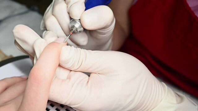 Closeup of a nail technician treating cuticle and nail folds. Beauty concept