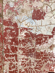 Old shabby concrete cracked white textured wall painted with red burgundy colour. Wallpaper, background. Vertical. Selective focus