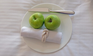 Two green apples on a white plate 