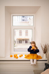 Little cute girl enjoy tangerines aroma sitting on the window