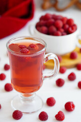raspberry drink on a gray stone background, walls, glass cup with compote, fresh raspberries on a wooden table, cooling drink