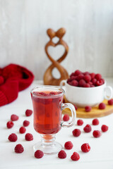 raspberry drink on a gray stone background, walls, glass cup with compote, fresh raspberries on a wooden table, cooling drink
