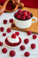 Raspberry jam in glass bowl with spoon isolated on white background