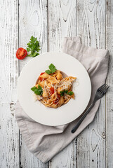 conchiglioni pasta with cherry tomatoes, cheese and parsley in white plate on wooden background