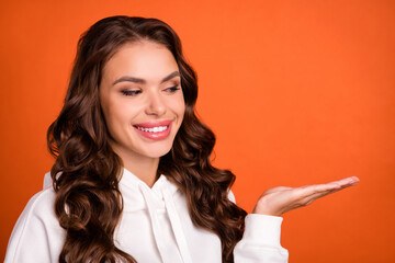 Photo of young girl good mood look product promo advertise sale isolated over orange color background