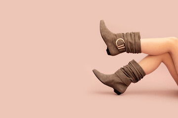 Beautiful Caucasian sexy woman's legs in beige brown suede short wide ankle buckle boots without...