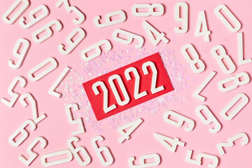 Pink background of numbers with lettering in the center 2022, decorated with Christmas sparkles
