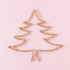 Golden Christmas tree shape on bright pink background. Minimal New Year concept with copy space. Holiday aesthetic layout.