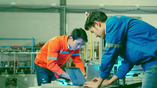 Co-working technician asian male engineer consult discussion laptop application result report discuss for quality control production line of cnc machine operate metal cutting work smart technology 