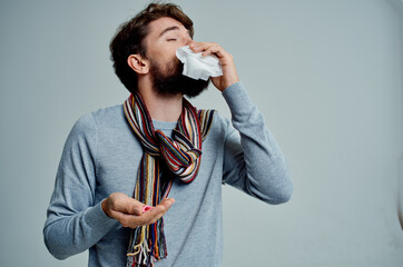 cold man in a sweater with a handkerchief infection light background