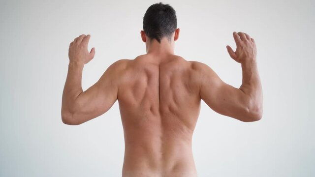 Athletic man suffers from back pain. Men's naked back on a white background. Body and skin care concept. Pimpled male skin.