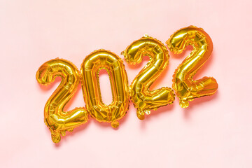 Gold foil balloons on pink background. Golden helium balloon number 2022. Happy New 2022 Year concept