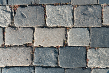 Old paving stones with chips and potholes in the city square texture or background