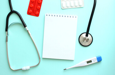 White notepad that lies next to the stethoscope on a blue background.