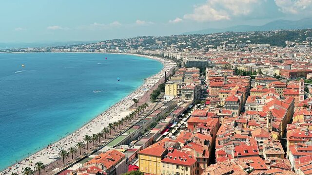 View of the cote d'Azur in Nice, France. Multiple resting on the beach people, buildings, blue water of the Mediterranean sea