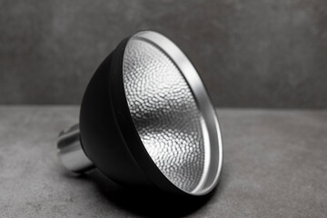 Small black speedlite flash light modifier reflector for illumination against a modern contemporary...