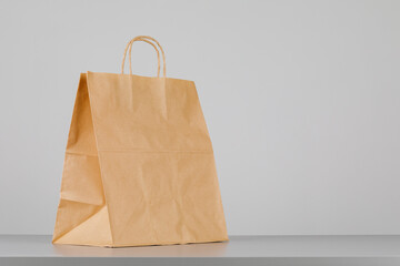 Brown paper bag with handles, empty shopping bag with area for your logo or design, food delivery concept.