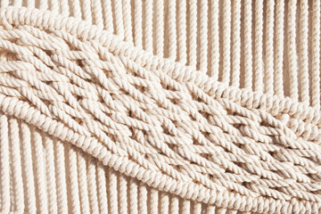 Fototapeta na wymiar Close-up of hand made macrame texture pattern. ECO friendly modern knitting DIY natural decoration concept in the interior. Handmade macrame 100% cotton. Female hobby.