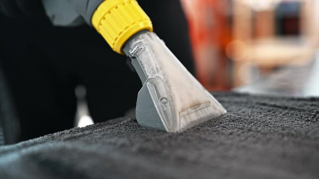 Working cleaner at car wash. Cleaning a carpet using a professional vacuum cleaner. Slow motion