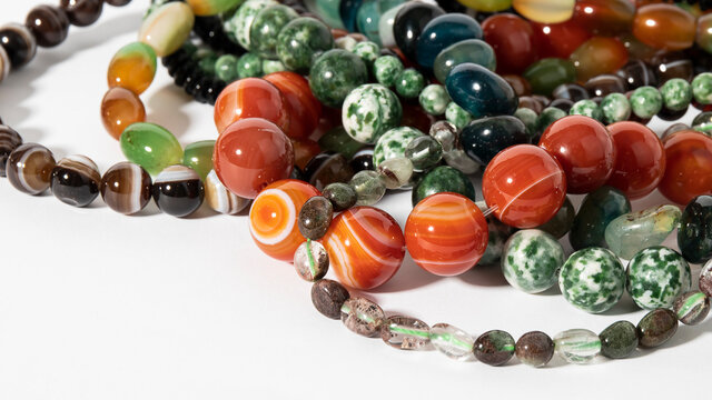 Different colorful beads made from natural stones on a white background. Isolated jewelry. 