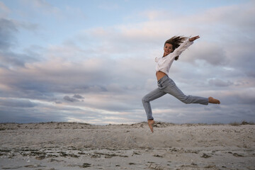 Beautiful woman dancing on beach at sunset