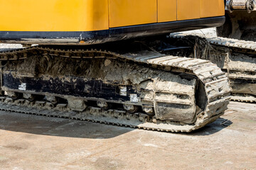 Dusty excavator wheels close up view on the construction site