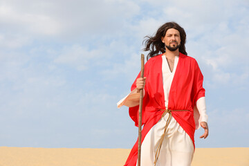 Fototapeta premium Jesus Christ walking with stick in desert. Space for text