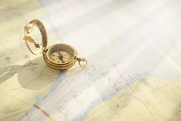 Retro style antique golden compass (sundial) and old nautical chart close-up. Vintage still life. Sailing accessories. Wanderlust, travel and navigation theme. Graphic resources, copy space © Alex Stemmer