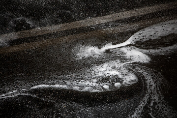 abstract background from a stream of water running down the drain on a car road in heavy rain, horizontal.