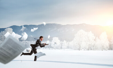 Naklejka na ściany i meble Businessman running in winter countryside