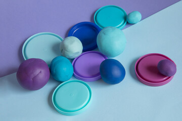 Modelling clay. Blue and purple plasticine balls with lids on paper background. Top view