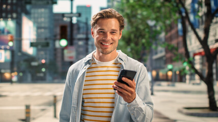 Portrait of a Handsome Young Man Wearing Casual Clothes and Using Smartphone on the Urban Street....