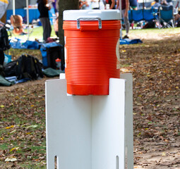 Orange water cooler on top of white boards in a park