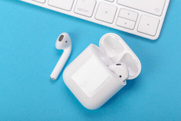 wireless bluetooth earphones with charging case on a blue background. The concept of modern...