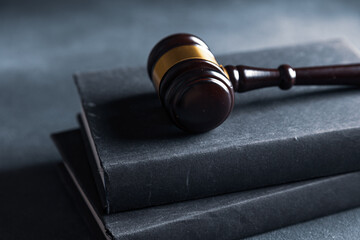 Law theme, judge gavel on a dark table with a book.