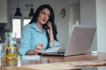 Businesswoman using a laptop and a smartphone while working from home