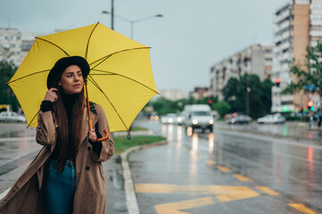 Young beautiful woman using a smartphone and holding a yellow umbrella
