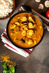 Mushroom curry. Homemade spicy mushroom curry in a black bowl on a dark background. Vegan food, Indian cuisine.