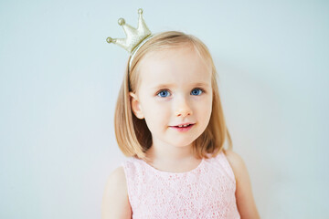 Adorable little girl in pink dress and golden crown dressed as princess