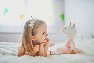 Adorable little girl dressed as princess playing with unicorn