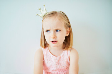 Adorable little girl in pink dress and golden crown dressed as princess