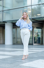 Fototapeta premium blonde woman talking on mobile phone in front of an office building
